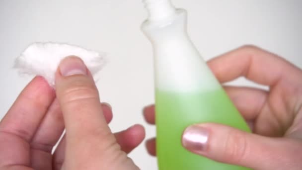 Manos femeninas sobre fondo blanco están sosteniendo una almohadilla de algodón y empapar con removedor de esmalte de uñas verde sin acetona — Vídeo de stock