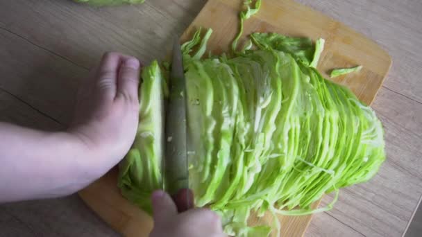 Γυναικεία χέρια κομμένα πράσινο λάχανο λάχανο σε μια ξύλινη επιφάνεια του τραπεζιού κουζίνας, κορυφή θέα — Αρχείο Βίντεο