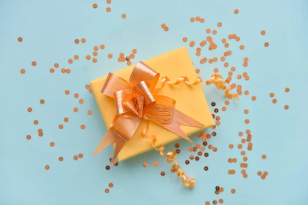 gift box with bright orange ribbon on a blue isolated background. Golden envelope with sequins on the background. holiday birthday, christmas congratulation surprise