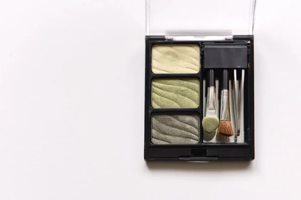 Amateur box with eyeshadow shades with a brush and tweezers for eyebrows on a white isolated background.