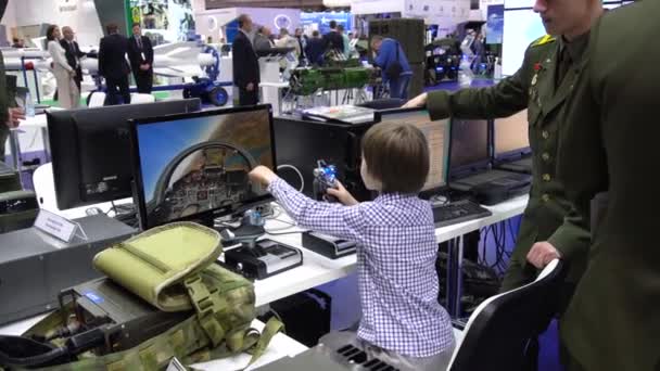 Wit-Rusland, Minsk, 17 mei 2019:9e internationale tentoonstelling van bewapening en militair materieel Milex-2019. Militair man leert jongen kind Aviation Simulator voor een militaire vliegtuig piloot op tentoonstelling — Stockvideo