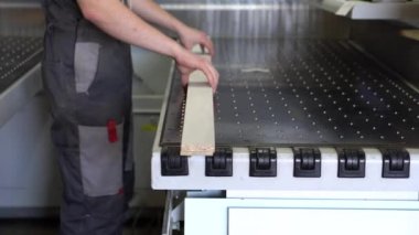 İşçi adam bir formatta lamine sunta bir parça alır-mobilya üretim fabrikasında sayısal program kontrolü ile raskroyechny Merkezi