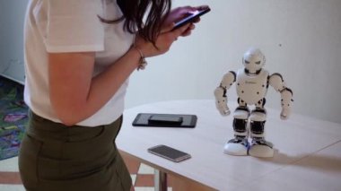 Belarus, Minsk, Robot Sergisi, Haziran 3, 2019: telefon setleri kadın kontrolleri kapalı masada beyaz plastik robot dansları komutları
