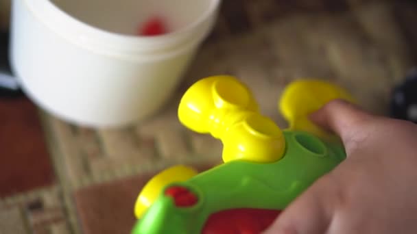 A criança joga em casa em um sofá com o jogo de edifício de desenhista na forma de um dinossauro. Crianças dedos coletar um brinquedo de quebra-cabeça colorido brilhante com uma chave de fenda . — Vídeo de Stock