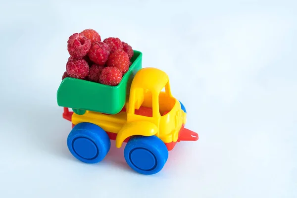 raspberries natural vitamins are in the back of truck in a childrens toy car food delivery truck logistics