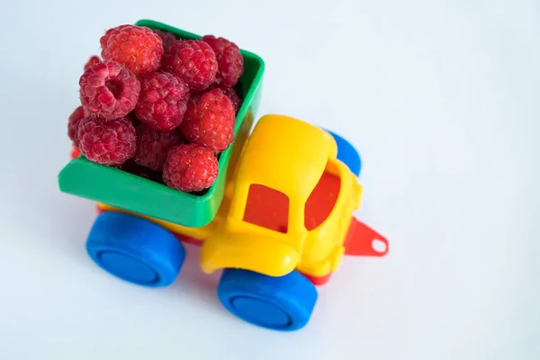 raspberries natural vitamins are in the back of truck in a childrens toy car food delivery truck logistics