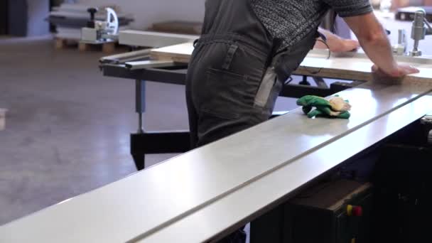 Pracujący człowiek produkuje na specjalnej maszynie do produkcji mebli części z płyt wiórowych — Wideo stockowe