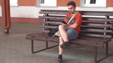 sıkılmış adam dışında bankta oturan ve telefonda yazarak