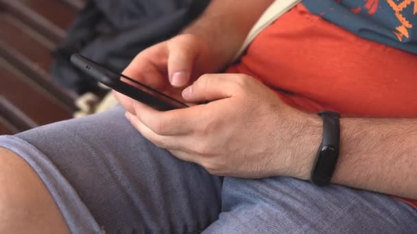 Manos masculinas sosteniendo el teléfono móvil moderno, el hombre está escribiendo sms, charlando con amigos, de cerca — Vídeos de Stock