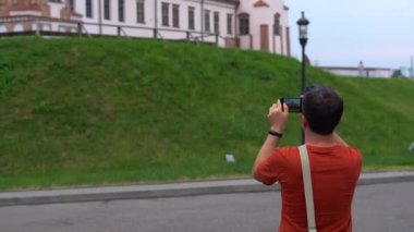 Mutlu gülümseyen Türk turist Mir Kalesi'nde Belarus turunda telefonunda fotoğraf ve video çekiyor