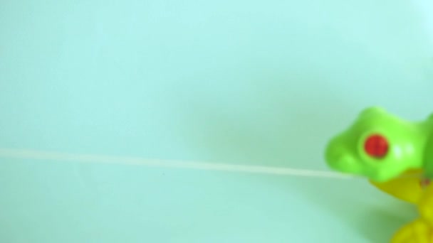 Dinosauro giocattolo di plastica verde giochi per bambini cavalca filo su uno sfondo blu monocromatico — Video Stock
