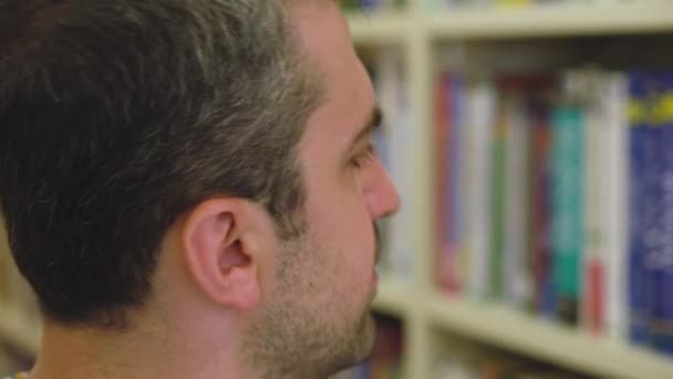 Турецький студент вибирає книгу на полиці в бібліотеці крупним планом — стокове відео