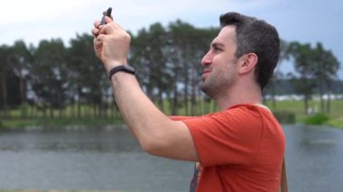 Mutlu gülümseyen Türk turist Mir Kalesi'nde Belarus turunda telefonunda fotoğraf ve video çekiyor