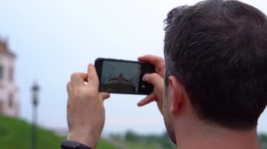 Mutlu gülümseyen turist adam Mir Kalesi'nde Belarus turunda telefonunda fotoğraf ve video çeker. yakın çekim, arka görüş