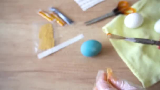Préparez-vous pour de joyeuses vacances de Pâques. Dans les mains du maître, dans le processus de peinture décorative manuelle des œufs de Pâques, la peinture saupoudre un pinceau sur la surface d'un œuf bleu. gros plan sur — Video