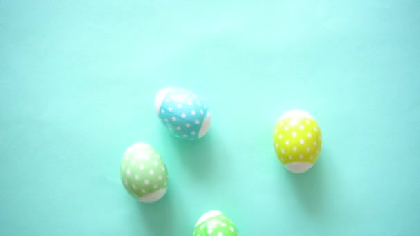 Барвисті великодні яйця пастельний тон з принтом гороху хаотично обертається, як варені на синьому фоні — стокове відео