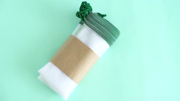 Белый прозрачный ткацкий капюшон мешки для многократного использования при покупке и хранении фруктов и овощей лежать на синем фоне рядом с пластиковыми пакетами — стоковое видео