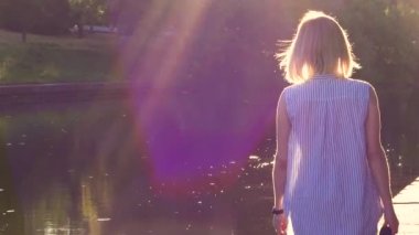 nehir ve bisiklet yolları boyunca gün batımında akşam bir iş gününden sonra yürüyen genç kadın, arka ışık