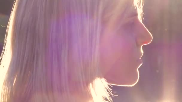 Молодая блондинка крупным планом портрет на закате в подсветке развивать волосы природа — стоковое видео