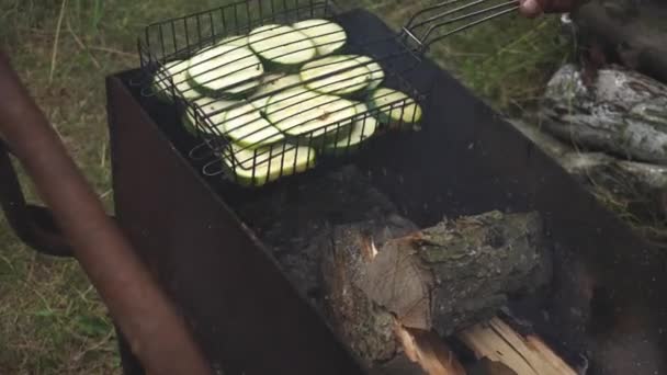 Сырые цуккини на гриле на деревенском гриле в саду поджаривают на углях и коптят — стоковое видео