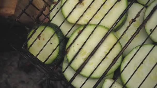Rohe Zucchini auf dem Grill auf rustikalem Grill im Bauerngarten wird auf Kohlen gebraten und in Großaufnahme geräuchert — Stockvideo