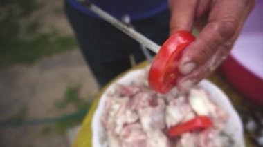 Yemek kebapları. Erkek el dışında bir yaz günü şiş üzerinde domates parçaları dizme. marine et ve domates ahşap bir arka plan rustik yaşam tarzı delinmiş