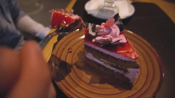 El primer plano de la mano de un hombre, romperlo y comer pedazo de pastel con un tenedor en una mesa en un café en el interior. primer plano — Vídeos de Stock