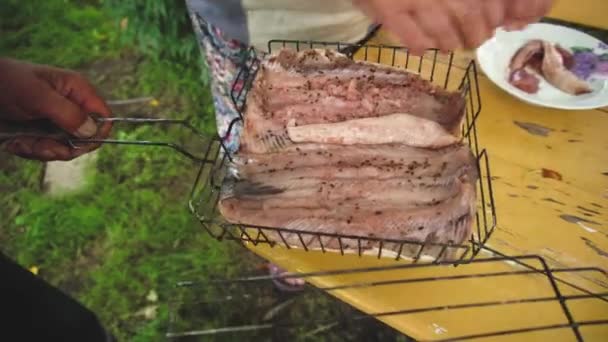 Par de manos de hombres y mujeres prisioneros poniendo carne al pescado para asar de cerca - Concepto de cocinar barbacoa y compartir una comida al aire libre. Estilo de vida — Vídeo de stock