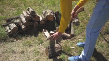 Çimenlerin üzerinde odun doğrama. Genç bir adam bir yaz günü barbekü yangın yapmak için bahçede açık odun doğrayın