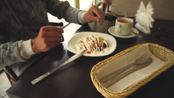 Обрезанный образ человека во время обеда, готового есть свежий салат с майонезом, сидящего за деревянным столом, медленно перемешивает ингредиенты — стоковое видео