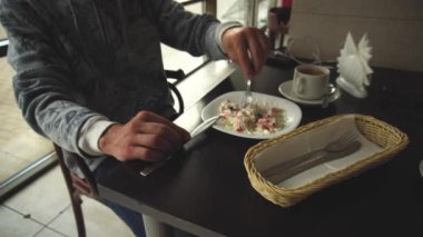 Ahşap masada otururken bir salata yiyor bir öğle molası sırasında bir adamın kırpılmış görüntü ve garson bir pancake getiriyor