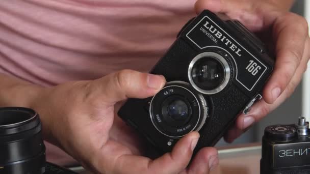 Wit-Rusland, Soligorsk, 1 juli 2019: handen van een mannelijke fotograaf Controleer de prestaties van een oude Sovjet-Wide-formaat analoge film retro camera in een fotostudio en richt zich — Stockvideo