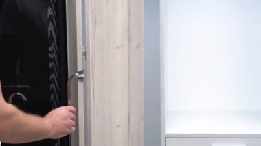 Mans el boş bir gardıropla kapıyı açar. çekmeceleri test eder ve aksesuarları inceler. mağazada mobilya örneği