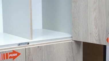 bir Mans el Push basarak boş bir dolap kapısını açar. çekmeceleri test eder ve aksesuarları inceler. mağazada mobilya örneği