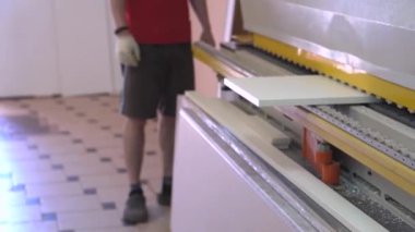 İşçi adam bir formatta lamine sunta bir parça alır-mobilya üretim fabrikasında sayısal program kontrolü ile raskroyechny Merkezi