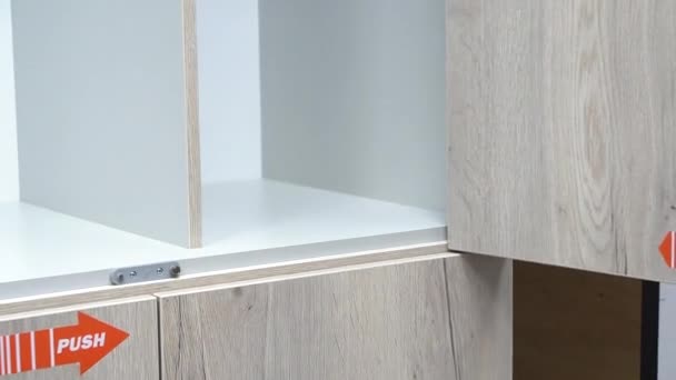 Een Mans hand opent de deur van een lege kast door op push te drukken. test laden en onderzoekt accessoires. voorbeeld van meubilair in de winkel — Stockvideo