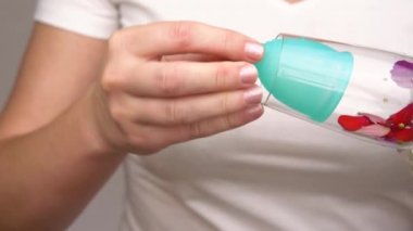 Kadın el kırmızı çiçekler gösterir, ince bir kadının kişisel hijyen ürünleri için kadın adet dönemi gösterir. kırmızı yaprakları içinde mavi bir adet fincan içine kan damlaları gibi düşmek