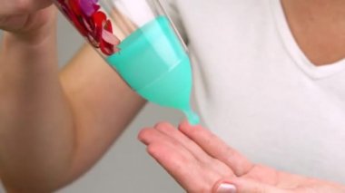 kadın el kırmızı zinnia çiçekleri ince kadın kişisel hijyen ürünleri için kadın adet dönemi göstermek gösterir. kırmızı yaprakları mavi bir adet fincan içine kan damlaları gibi düşmek