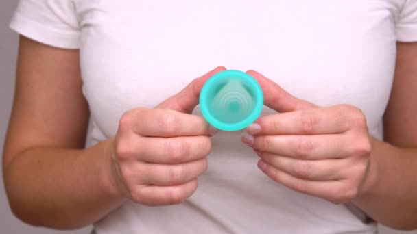 Hände einer jungen Frau zeigen die blaue Menstruationstasse aus nächster Nähe, ein Körperpflegeprodukt während der Menstruation — Stockvideo