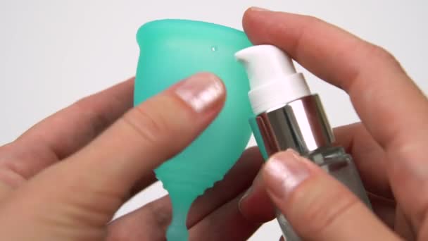 Womans hand uses lubricant to lubricate the menstrual cup intimate personal hygiene product for a comfortable installation during period time close-up — Stock Video