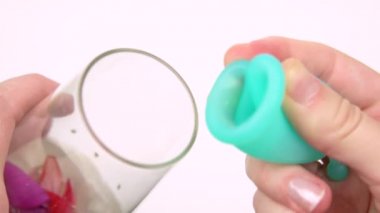 kadın el kırmızı zinnia çiçekleri ince kadın kişisel hijyen ürünleri için kadın adet dönemi göstermek gösterir. kırmızı yaprakları mavi bir adet fincan yakın içine kan damlaları gibi düşmek