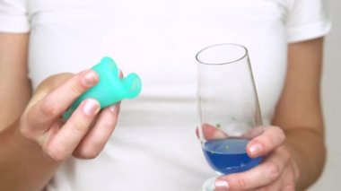 genç bir kadının elleri şeffaf bir cam ve mavi sıvı ile adet fincan çalışmalarını göstermektedir. dönem boyunca samimi hijyen ürünü