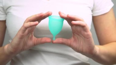 genç kadının elleri yakın çekim mavi adet fincan, adet sırasında kişisel bir hijyen ürünü göstermek
