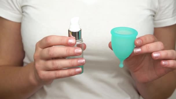 Kvinnans hand använder smörjmedel för att smörja menstruations cupen intima personlig hygienprodukt för en bekväm installation under period tid närbild — Stockvideo