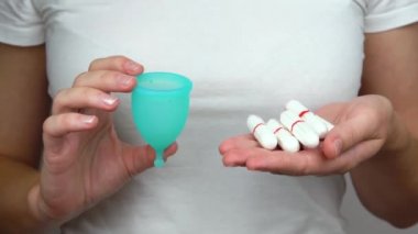 kadın karşılaştırmak ve adet sırasında kişisel hijyen ürünleri seçmek için elinde tampon ve mavi adet fincan tutar