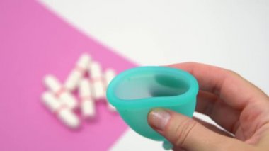 genç kadının elleri yakın çekim mavi adet fincan sert çeşitli göstermek, sıhhi tamponarka planda adet sırasında kişisel bir hijyen ürünü, pembe bir arka plan üzerinde bir alternatif olarak