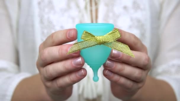 Ženská ruka prokazuje modrý menstruační pohár se zlatým úklonem jako bonus nebo dar, produkt osobní hygieny v době menstruace — Stock video