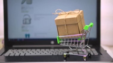 Dizüstü bilgisayar klavyesinde market arabasında kutu. bir online bakkal arka plan aleyhine. teslimat ile ev için online alışveriş