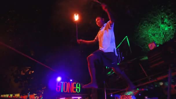 Tailandia, Phi Phi Island, 28 de septiembre de 2019: espectáculo de fuego en la playa abierta. Balanceador masculino enfocado se para en una cuerda malabares bolas de fuego en la noche al aire libre — Vídeos de Stock