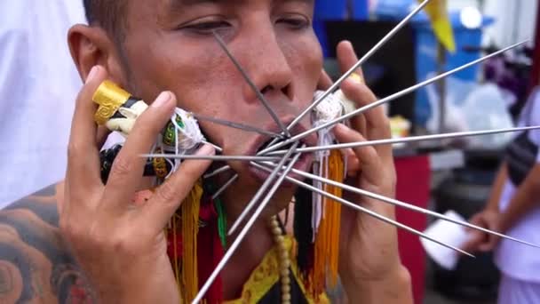 タイ、プーケット、 2019年10月7日:プーケットタウンで毎年開催されるベジタリアン・フェスティバルで、金属製の編み物針で頬を刺し込まれた中国系タイ人の男性のクローズアップ肖像 — ストック動画